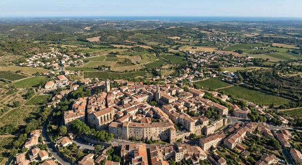 Photographie aérienne ou vue panoramique de la région de Pézenas dans l'Hérault, montrant le paysage typique de la région (habitat urbain ou semi-urbain, vue d'ensemble des zones résidentielles et commerciales). L'image doit présenter une perspective claire du territoire couvrant la zone d'intervention de 50 km autour de Lignan-sur-Orb, sans texte, logo ou filigrane visible.
